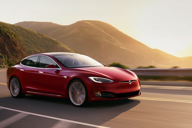 "red tesla on a hilly road"