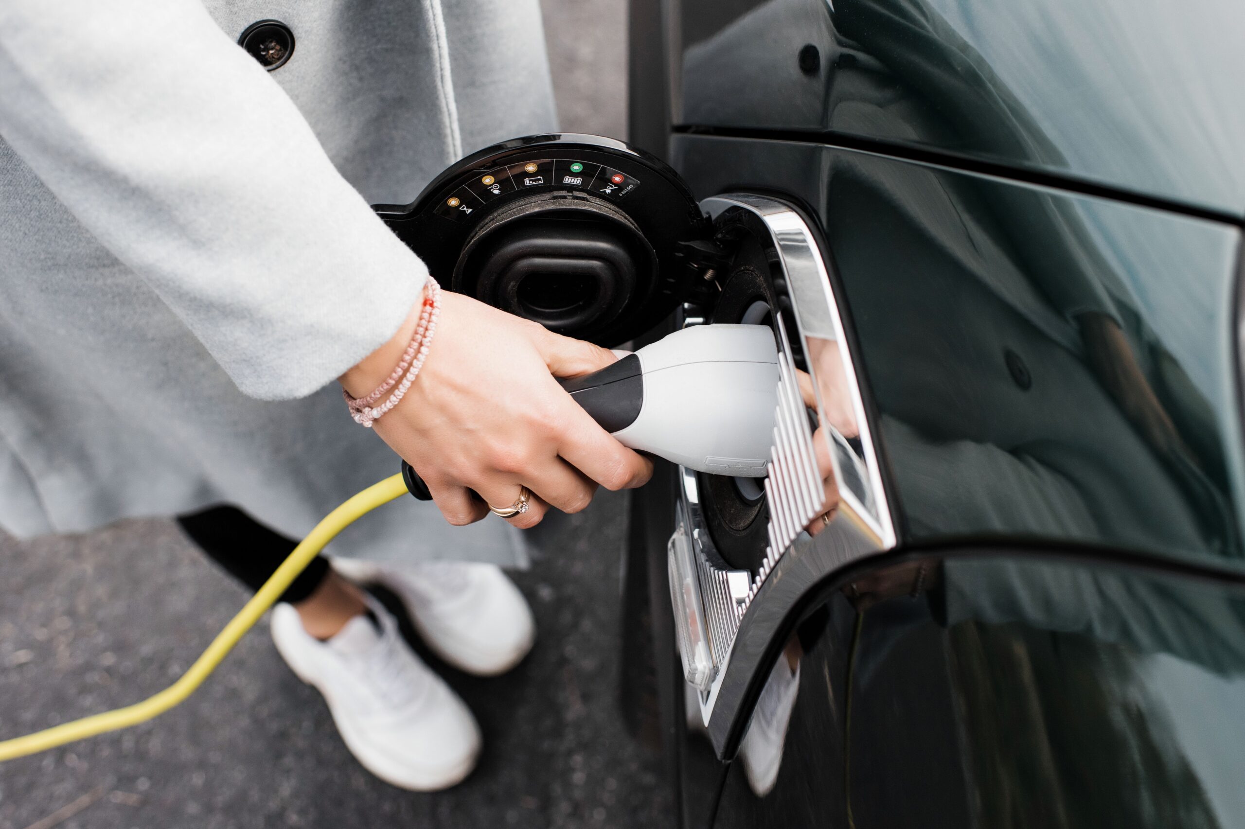 woman's hand plugging in a charging lead to her electric car