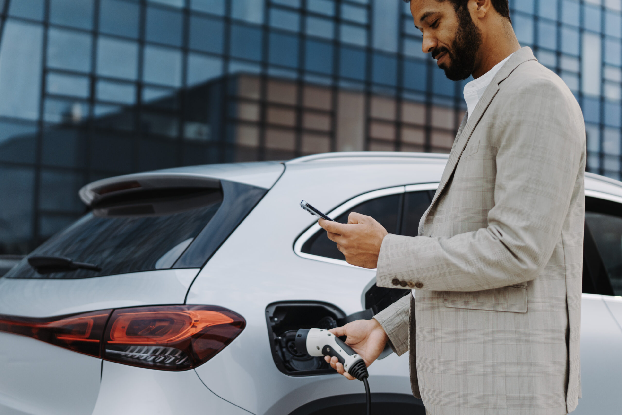 Young multiracial businessman charging his car.