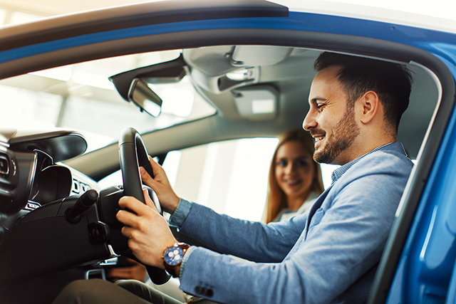 Young couple choosing new car for buying in dealership shop