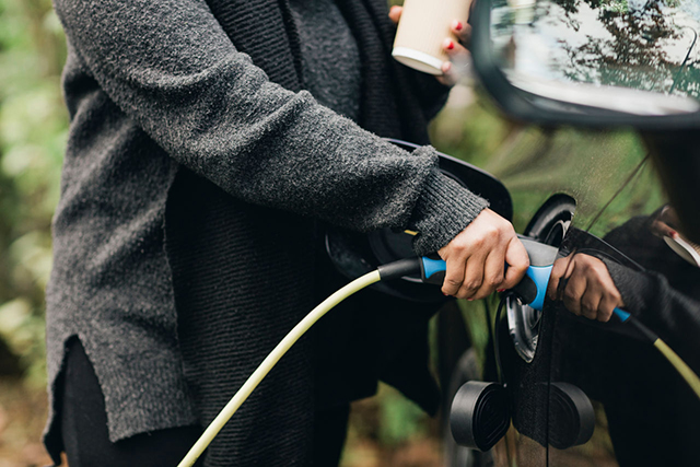 Midsection of mid adult woman charging electric car